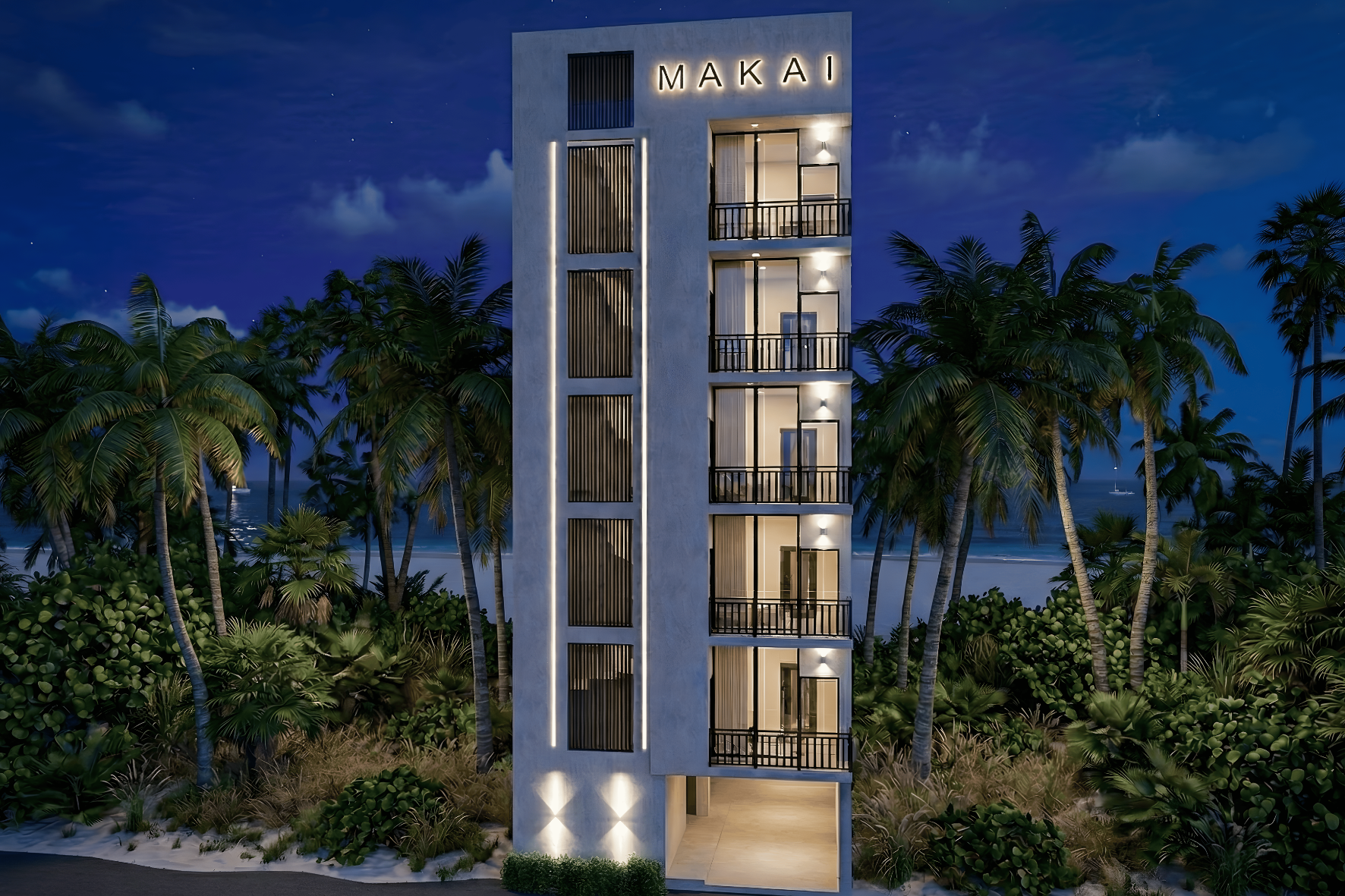 Night view of a white, multi-story building labeled MAKAI with lit balconies, palm trees, and a beach in the background.