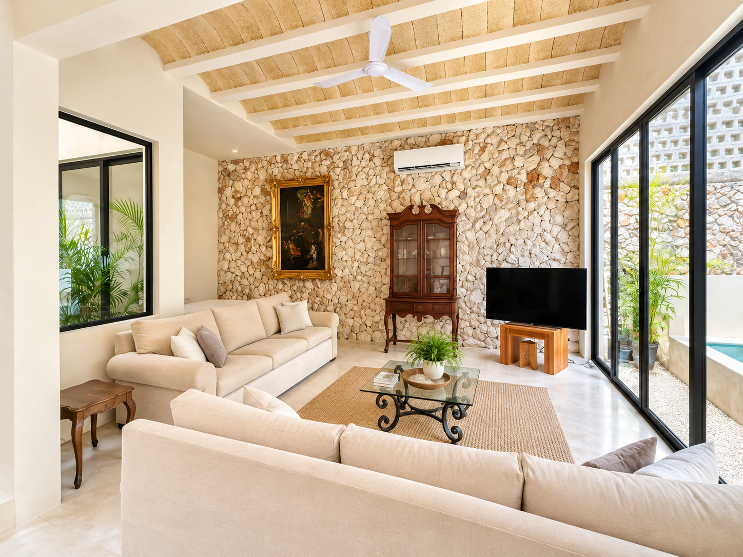 Bright living room with beige sofas, glass coffee table, and sliding doors opening to a patio.